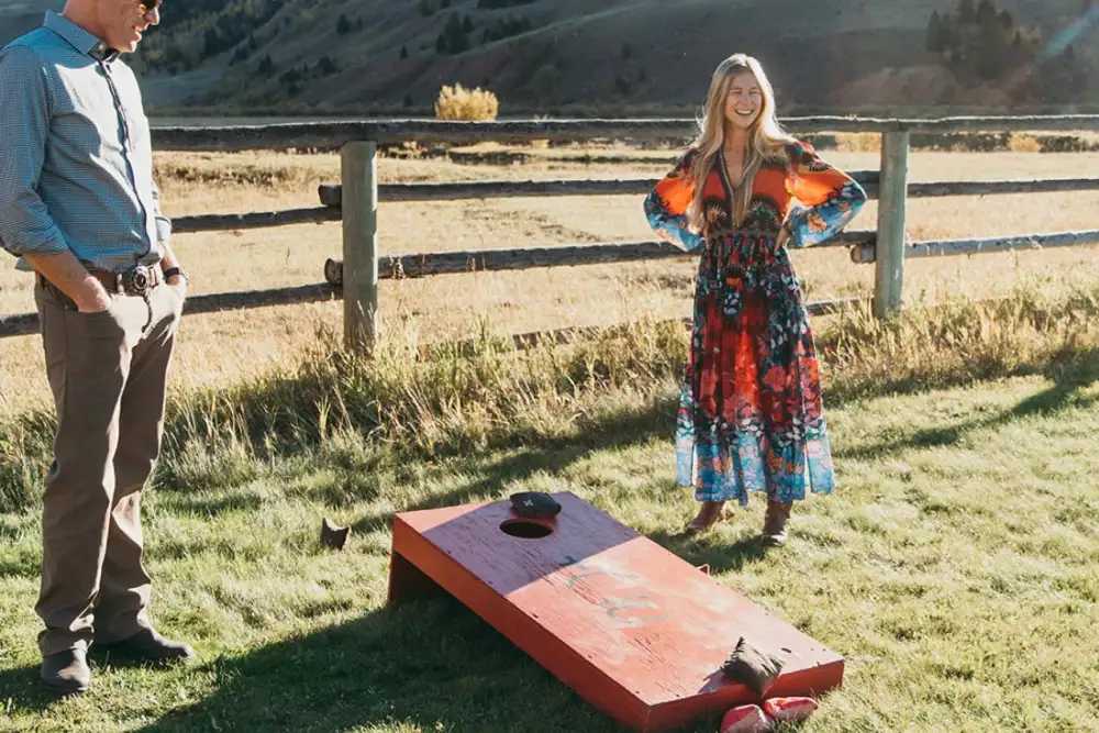 Two people posing in front of a bean bag game in a field