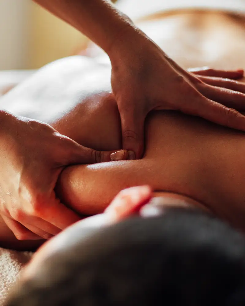 A person giving a massage to a man lying on a bed