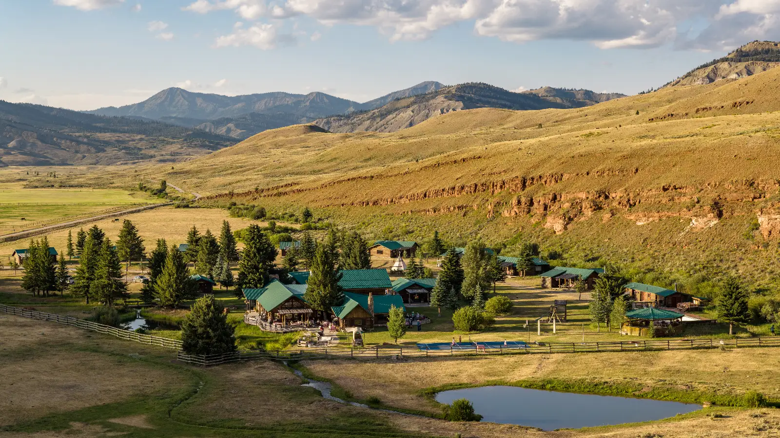 A valley with cabins and a lake, surrounded by trees and mountains