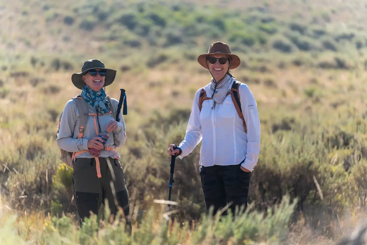 Two women in a field with hats and walking sticks