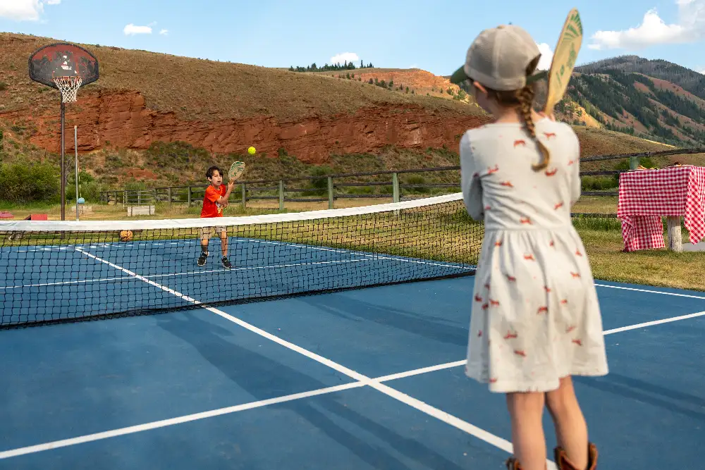 Two children playing tennis on a court