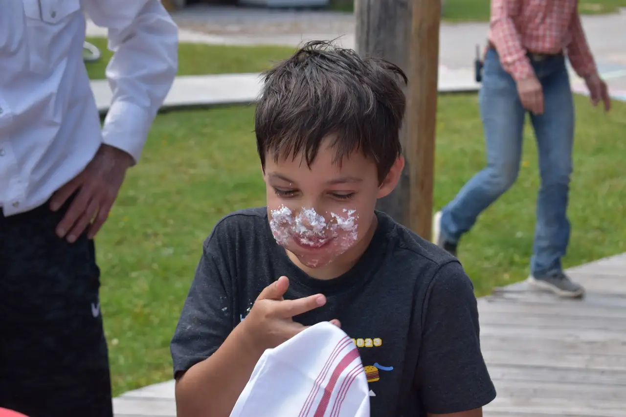 A young boy with cake on his face smiling