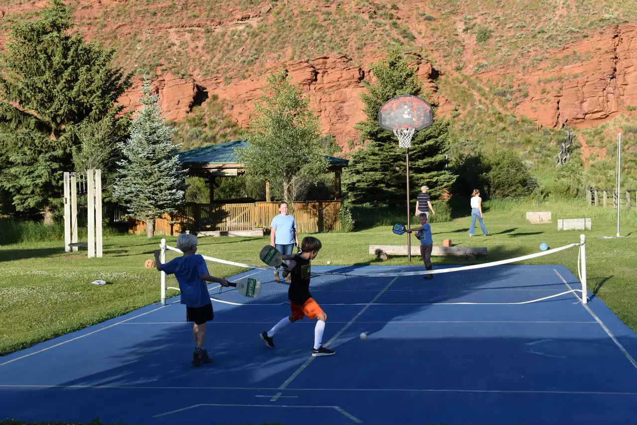 Children playing tennis on a blue court