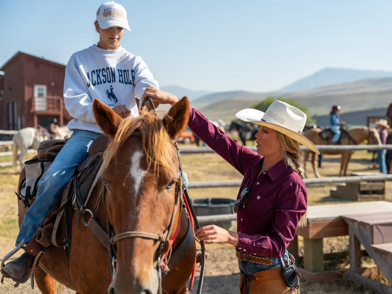 A woman petting a horse in a fenced area with other people around