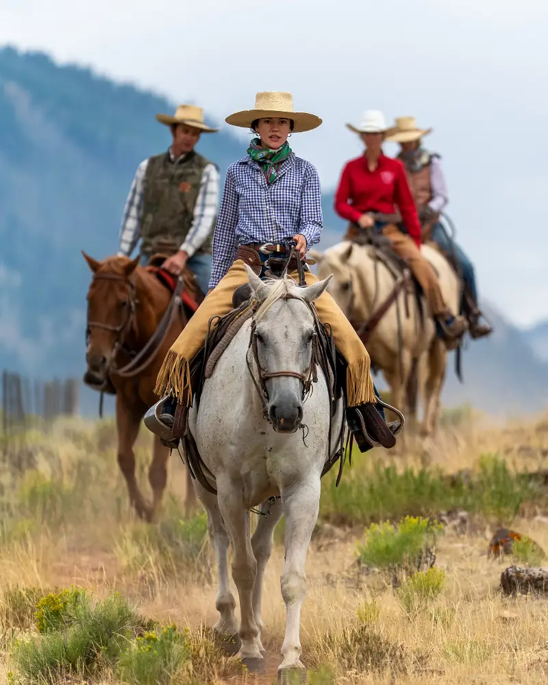 A group of people riding horses in a field