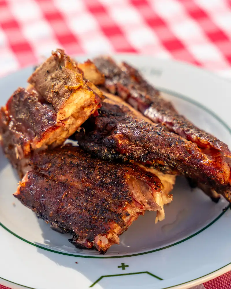 A plate of barbecue ribs on a checkered tablecloth