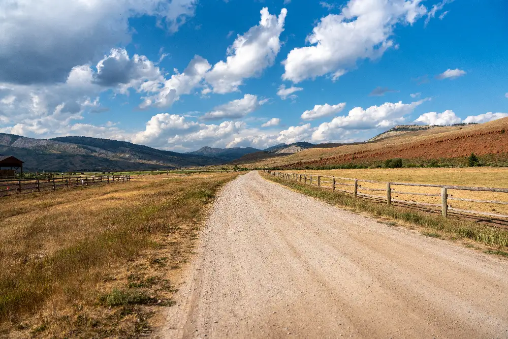 A dirt road with a fence on either side