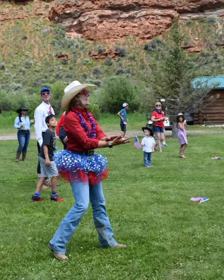 A woman in a patriotic dress throws a frisbee to a group of people in a field